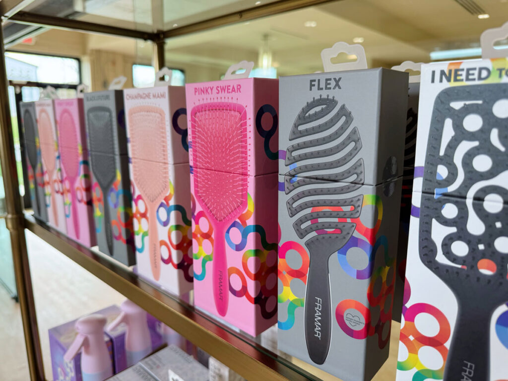 Boxes of colorful hair brushes labeled "Flex," "Pinky Swear," and others are displayed on a shelf in a well-lit store. - HC Beauty in Charlotte, Nc